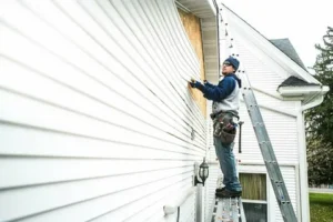 Worker mounting tan horizontal siding boards over exterior wall insulation